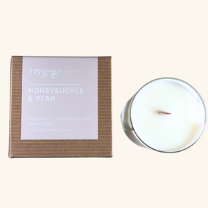 Honeysuckle & Pear Candle:
9 oz “Honeysuckle & Pear” coconut soy candle by Hygge Candle Co. in a light pink-labeled kraft box, hand-poured with a wooden wick.
