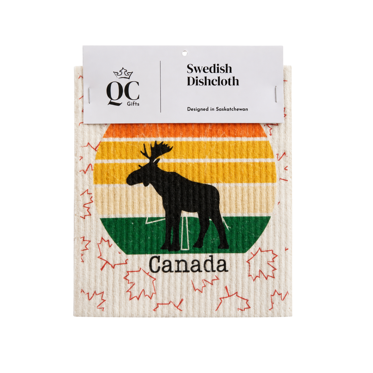 A packaged dishcloth from QC Gifts featuring a Canadian theme. The dishcloth has a cream-colored ribbed texture with a colorful retro sunset design in orange, yellow, and green, a black moose silhouette, and the word 'Canada' printed below.