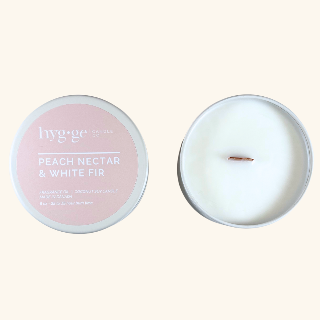 6 oz “Peach Nectar & White Fir” soy coconut candle in a blush tin by Hygge Candle Co., featuring a natural wooden wick and soft peach scent.