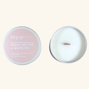 6 oz “Peach Nectar & White Fir” soy coconut candle in a blush tin by Hygge Candle Co., featuring a natural wooden wick and soft peach scent.