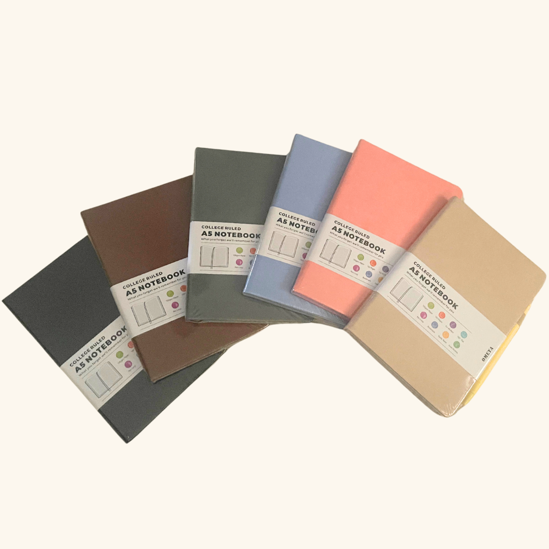 Stack of six A5 hardcover journals in assorted colours on a quilted background – perfect for gift boxes from QCGifts.ca.