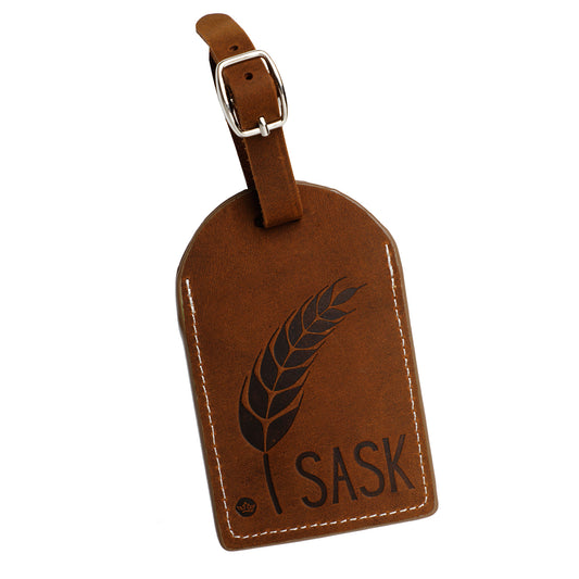 Brown leather luggage tag with 'I SASK' text and wheat design on a white background