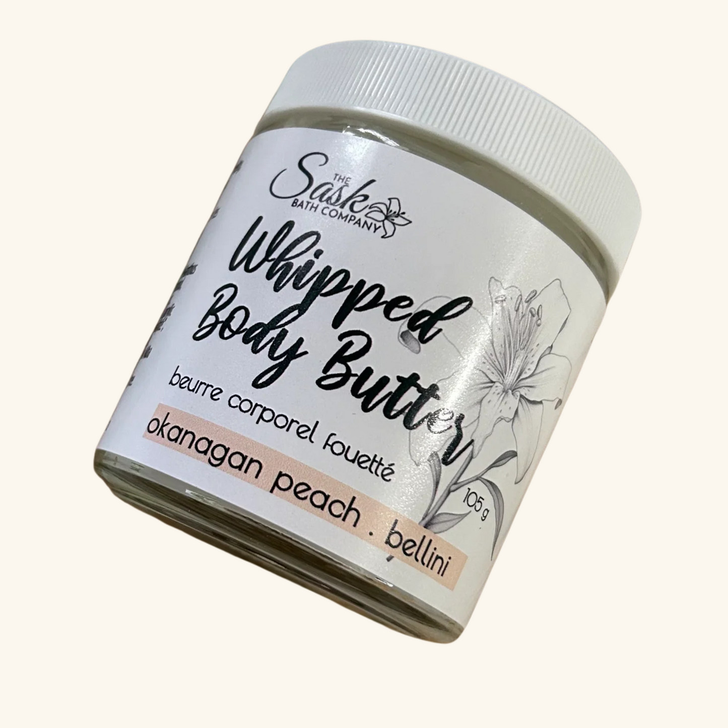 The Sask Bath Co. Whipped Body Butter in Okanagan Peach Bellini scent, shown in a 105g glass jar with illustrated flower detail.