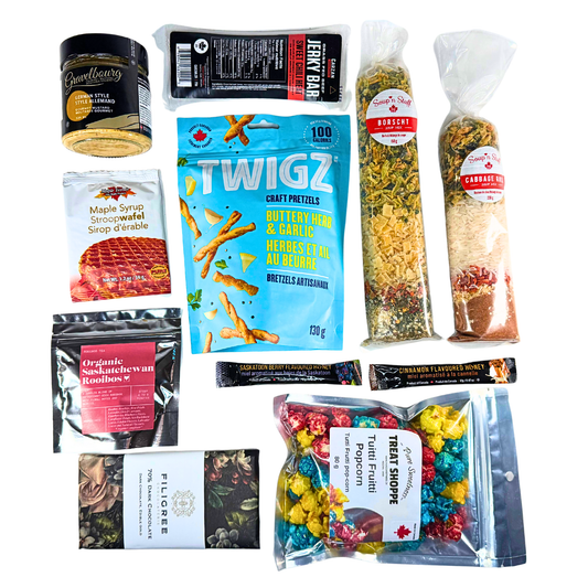 Overhead image of a Prairie Gourmet Sampler Box featuring Saskatchewan-made snacks, mustard, soups, chocolate, popcorn, and tea, neatly arranged for gifting.