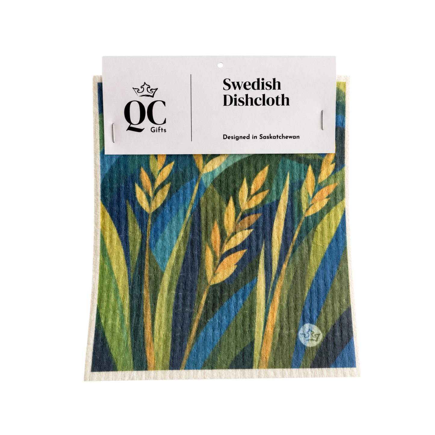 A packaged Swedish dishcloth with a colorful botanical pattern of blue, green, and yellow wheat stalks, featuring a white paper header card from QC Gifts.