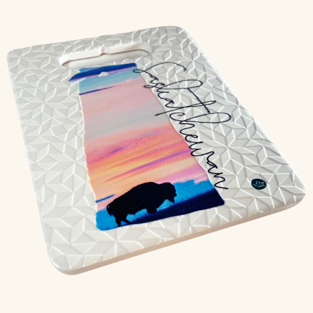 Collection of Prairie-inspired ceramic trivets, handcrafted in Turkey, featuring a bison sunset, Regina Prairie Lily, and Saskatchewan grain elevator design