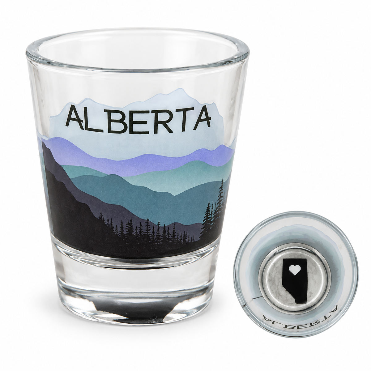 Alberta 1 oz shot glass with layered mountain and pine-tree artwork and an inset showing the province silhouette and heart in its base.