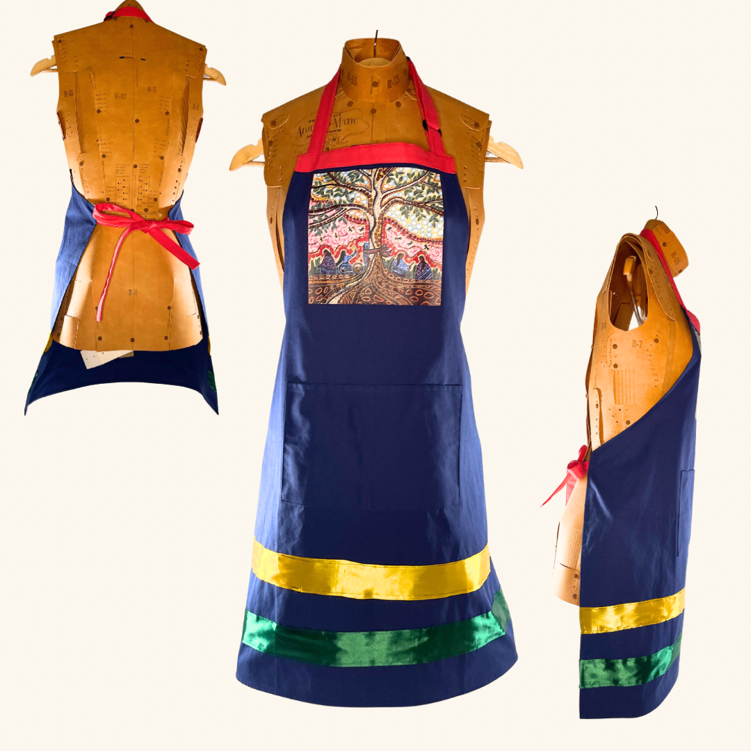 Collection of three handcrafted Prairie-inspired aprons, featuring the Saskatchewan & Prairie Lily design, Wheat Field & Grain Elevator canvas apron, and Leah Dorion’s 'Singing to the Aspen' apron