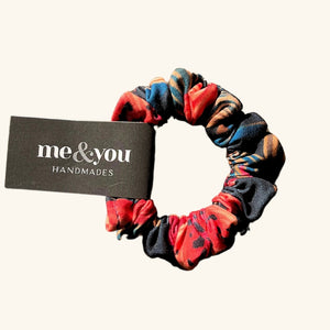 Me & You Handmades scrunchie featuring a bold red Prairie Lily pattern, a stylish and functional hair accessory