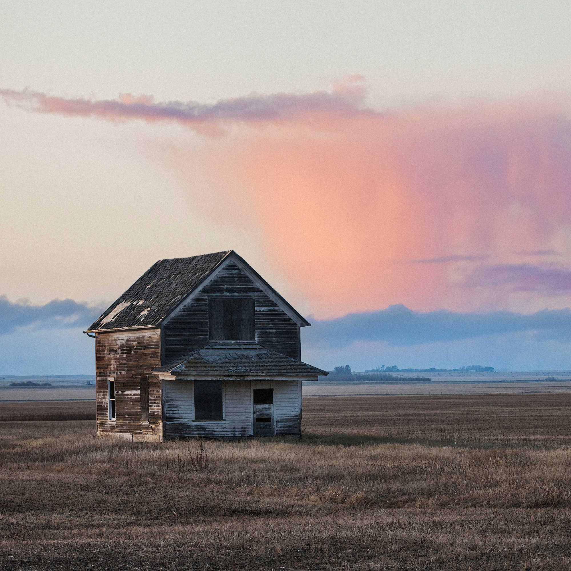 abandoned house A peaceful Prairie field at dusk, bathed in warm golden hues with a dramatic sky.