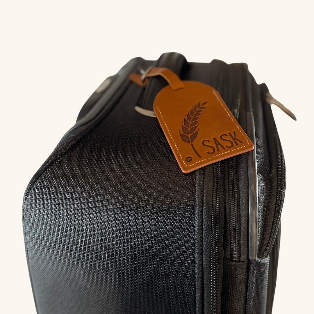 Prairie Wheat leather luggage tag attached to a suitcase handle, adding character and easy identification.