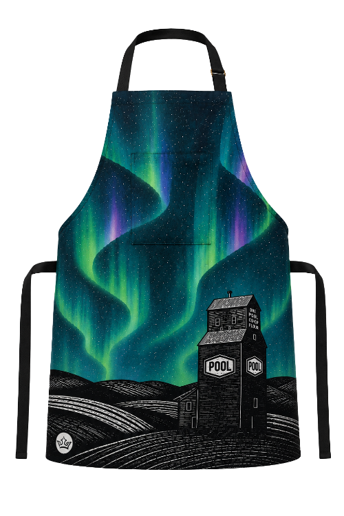 A black apron with a colorful print of the aurora borealis over a farm scene with silhouettes of fields, a grain silo labeled 'POOL', and a small crown logo near the bottom left.