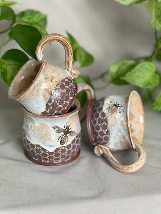 Hand-thrown ceramic honey pot mug filled with a warm drink, showcasing its rustic honeycomb design and artisanal craftsmanship